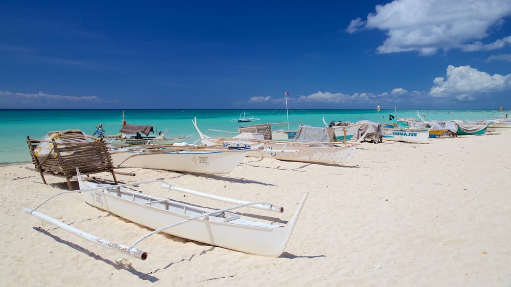 Ein Strand mit mehreren traditionellen Booten und einer Holzkonstruktion im Sand.