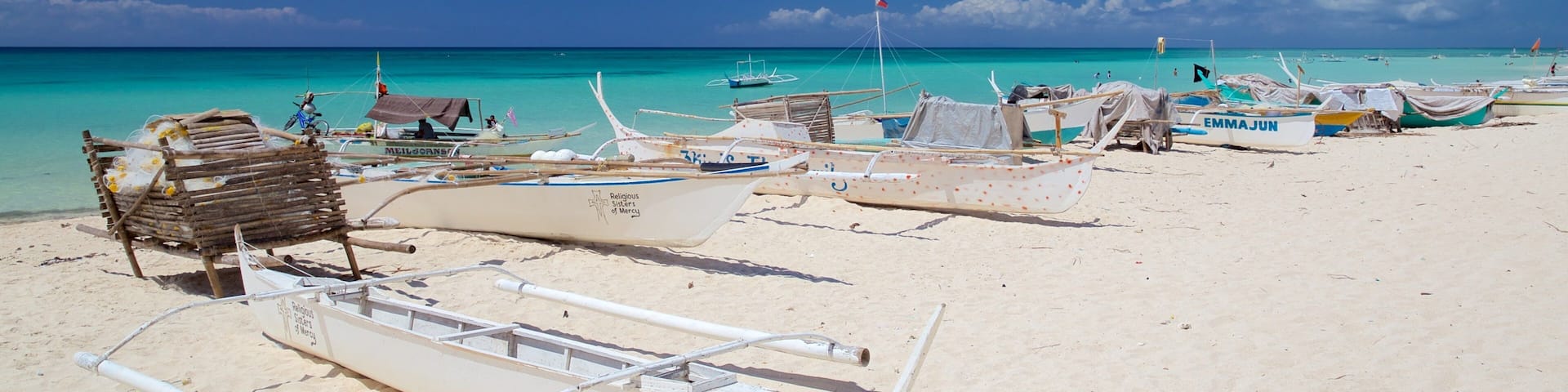 A beach with several traditional boats and a wooden structure on the sand.