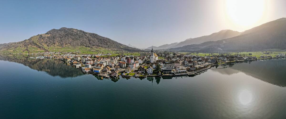 A lakeside town with a prominent church, surrounded by mountains and calm waters.