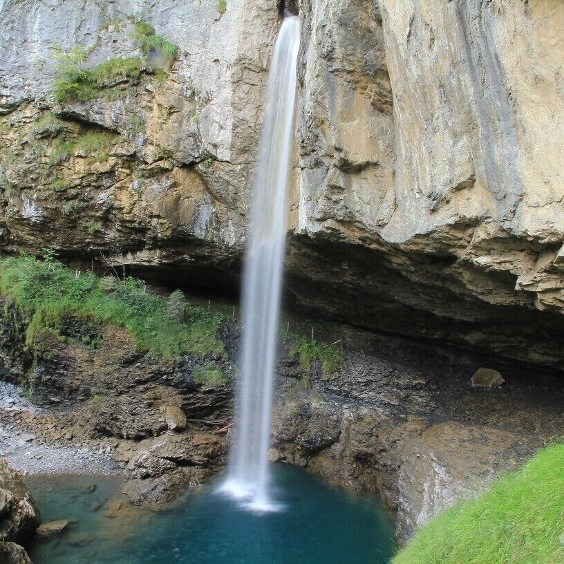 A waterfall cascading into a pool surrounded by rocky cliffs.