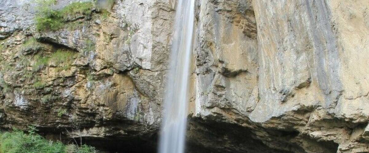 A waterfall cascading into a pool surrounded by rocky cliffs.