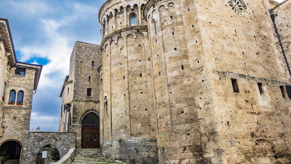 A historic stone building with a large arched entrance and a staircase leading up to it.