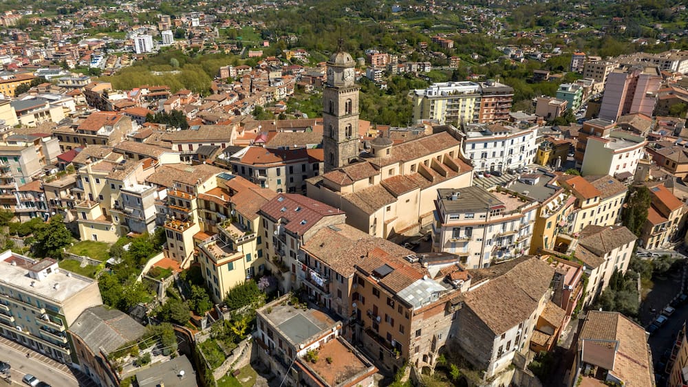 Un quartier urbain densément peuplé, caractérisé par des bâtiments historiques, une tour de l’horloge imposante et un mélange de bâtiments résidentiels et commerciaux.