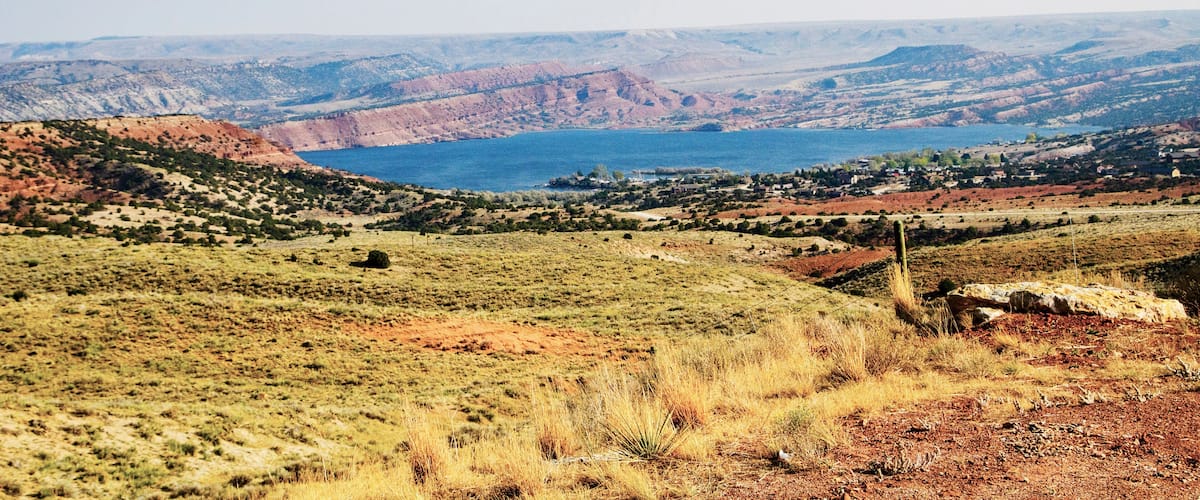 A vast landscape with rolling hills, a large body of water, and sparse vegetation.