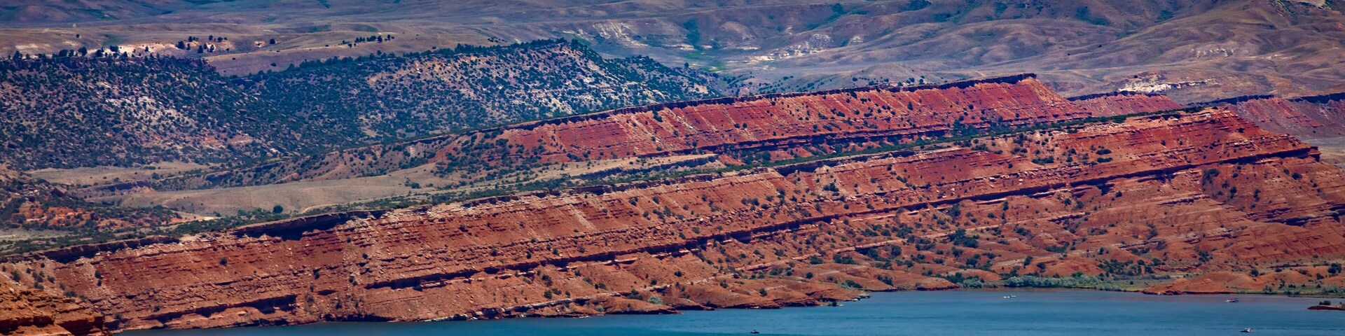 Un valle con un lago, formaciones rocosas rojas y edificios dispersos.
