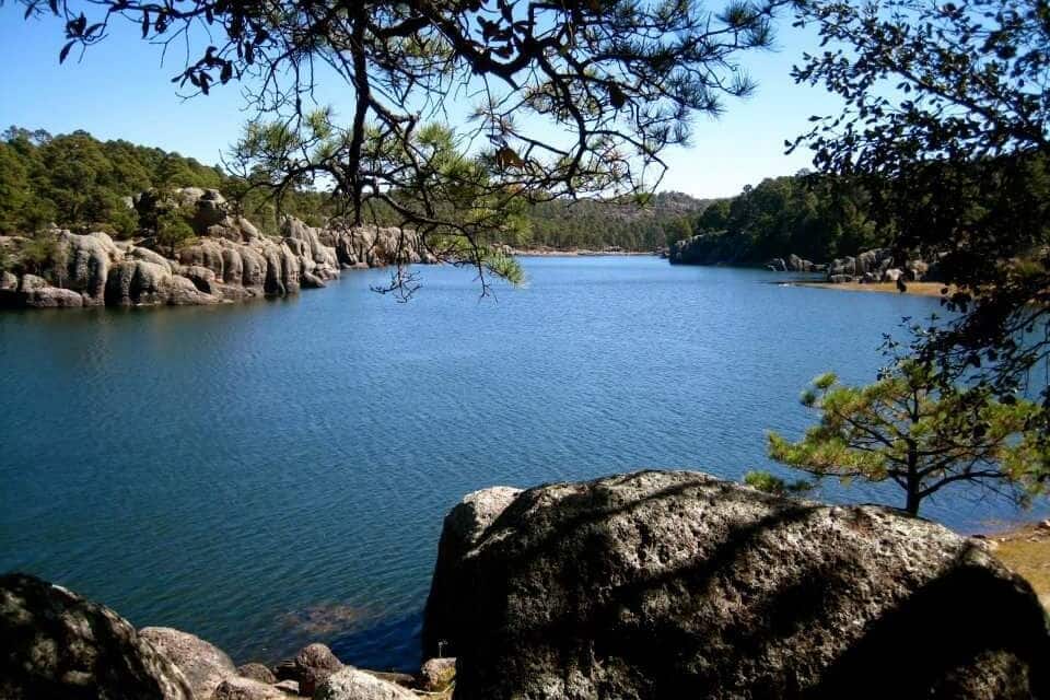 Un lago tranquilo rodeado de terreno rocoso y escasa vegetación.