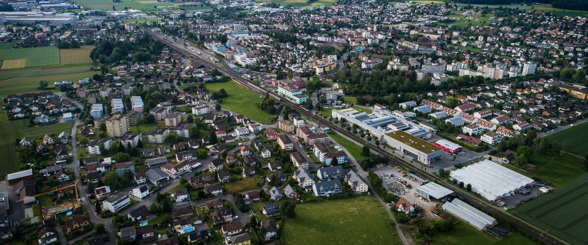 An aerial view of a town with residential areas, industrial buildings, and green fields.