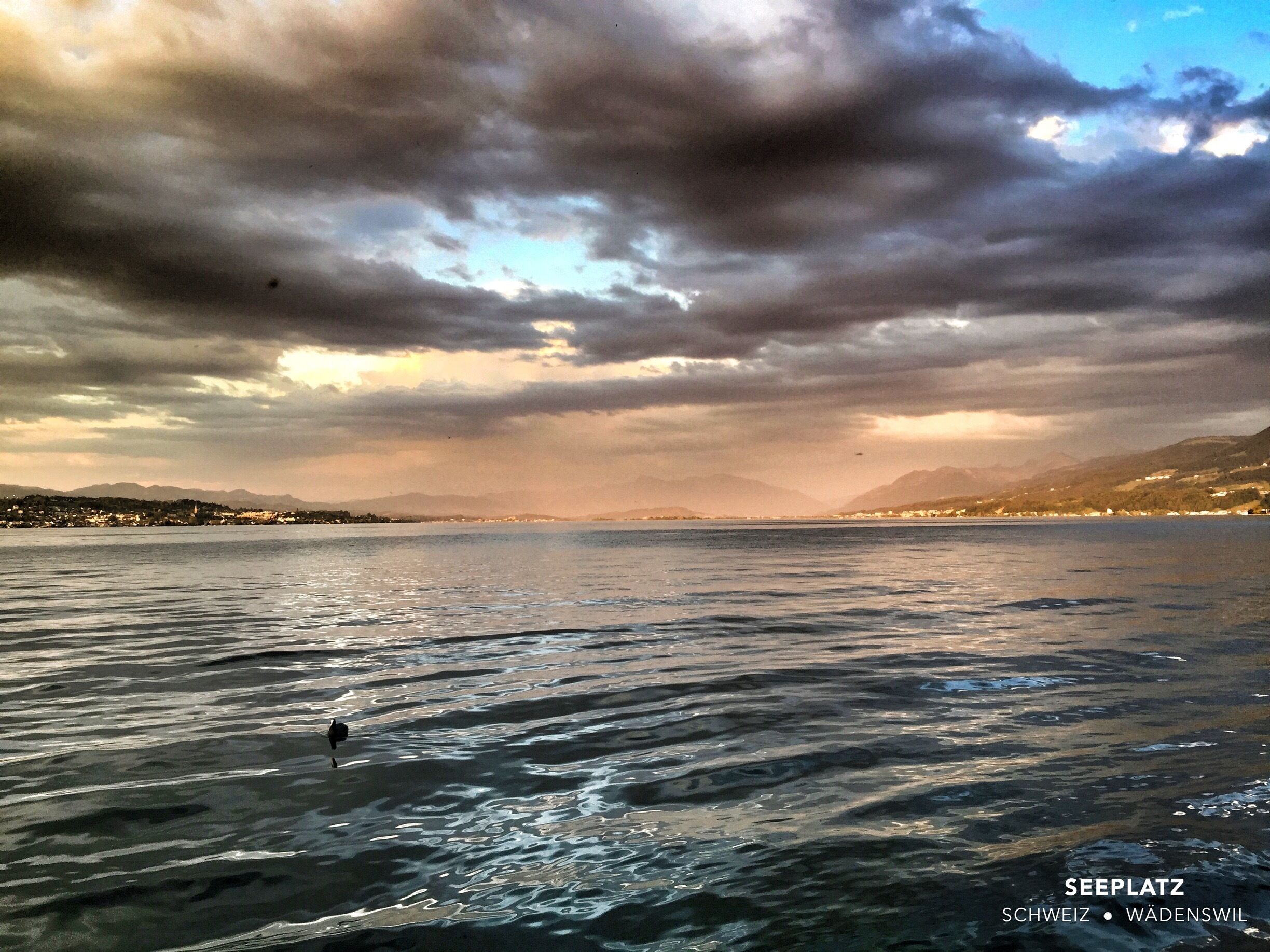 A body of water with a cloudy sky and distant mountains.