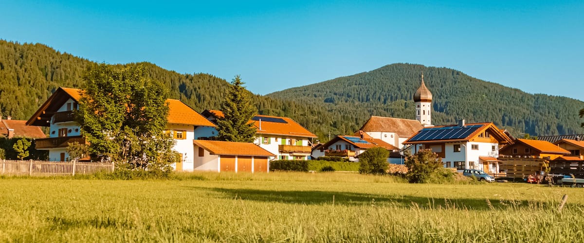 A village with traditional houses, a church, and a mountain in the background.