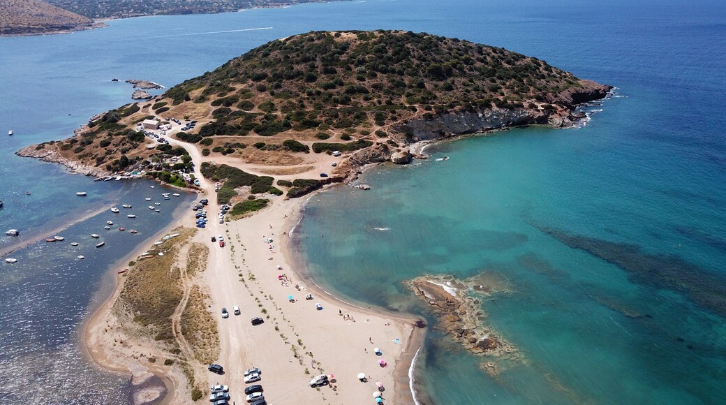 Vista aèria d'una zona costanera amb una platja de sorra, un petit turó amb vegetació escassa i embarcacions a l'aigua.
