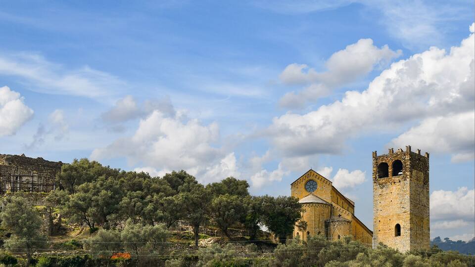 A historic church with a bell tower and a stone wall in the background.