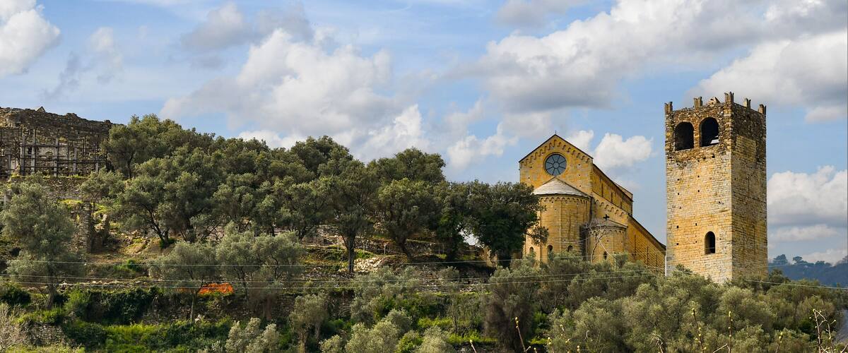 A historic church with a bell tower and a stone wall in the background.