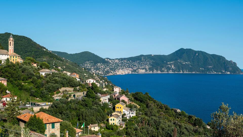 A coastal town with colorful houses, a prominent church, and a clear view of the sea.