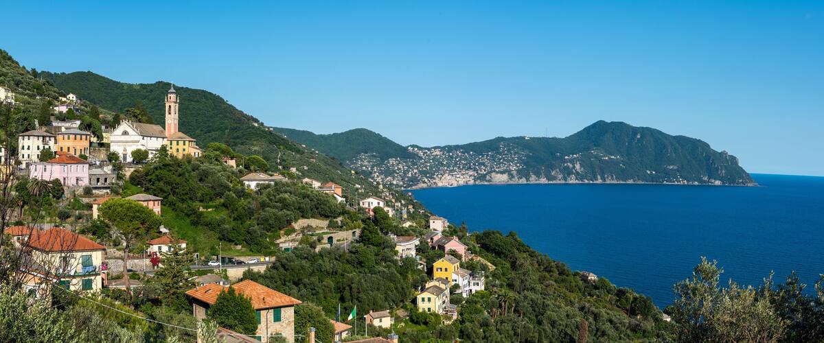 A coastal town with colorful houses, a prominent church, and a clear view of the sea.