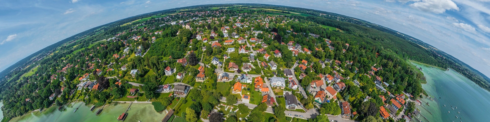 An aerial view of a coastal town with houses, a marina, and a large body of water.