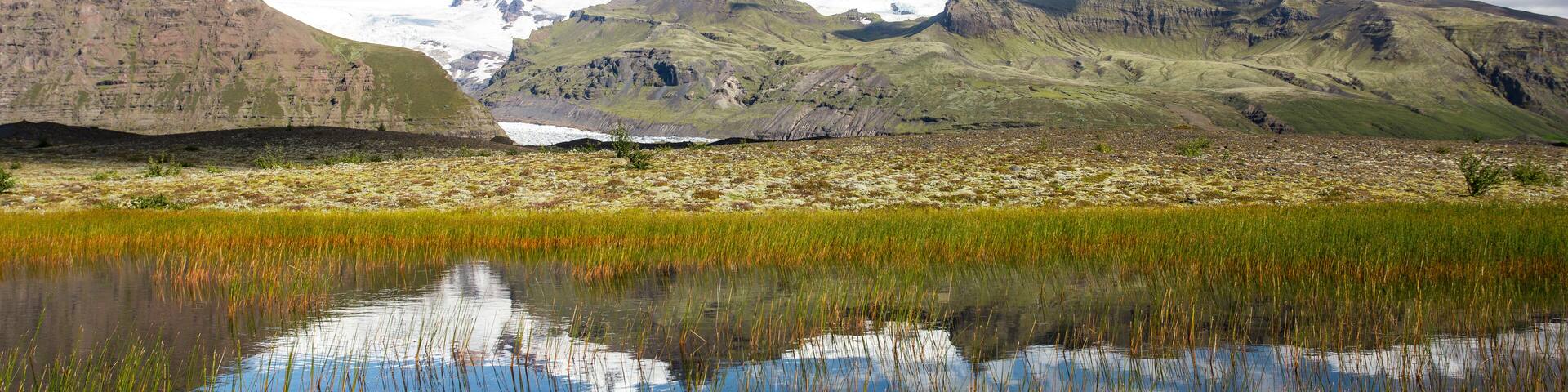 A mountainous landscape with a reflective lake and snow-capped peaks.