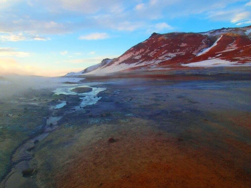 A glacier with a small lake and snow patches.