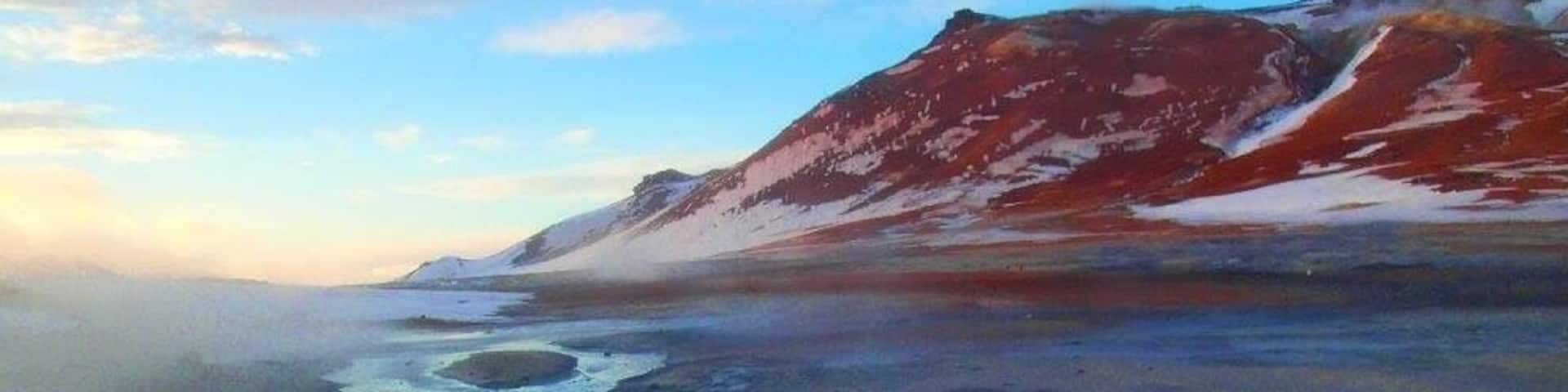 A glacier with a small lake and snow patches.
