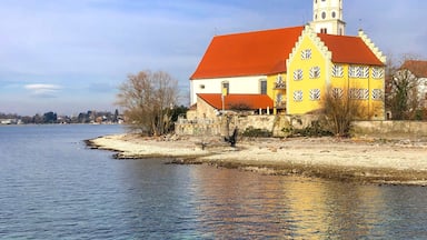 A river with a building featuring a red roof and a green dome.
