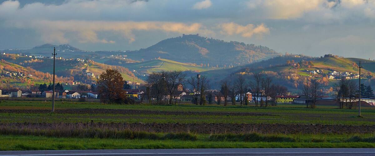 A rural landscape with rolling hills, a small village, and a distant castle on a hill.