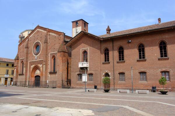 Un edificio storico in mattoni con una torre dell'orologio e finestre ad arco.