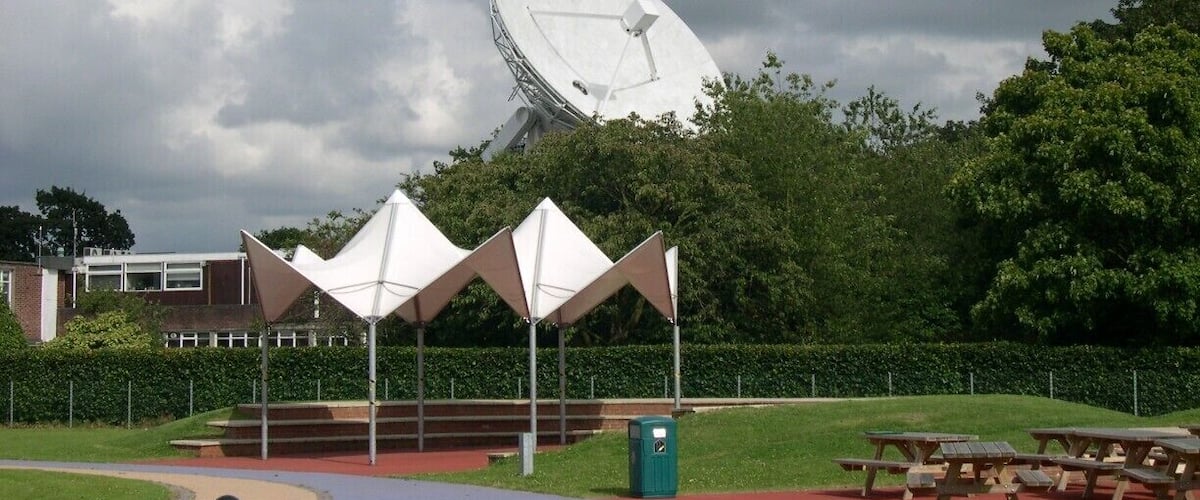 The Jodrell Bank Observatory (originally the Jodrell Bank Experimental Station, then the Nuffield Radio Astronomy Laboratories from 1966 to 1999; /ˈdʒɒdrəl/) is a British observatory that hosts a number of radio telescopes, and is part of the Jodrell Bank Centre for Astrophysics at the University of Manchester. The observatory was established in 1945 by Sir Bernard Lovell, a radio astronomer at the University of Manchester who wanted to investigate cosmic rays after his work on radar during the Second World War. It has since played an important role in the research of meteors, quasars, pulsars, masers and gravitational lenses, and was heavily involved with the tracking of space probes at the start of the Space Age. The managing director of the observatory is Professor Simon Garrington.
The main telescope at the observatory is the Lovell Telescope, which is the third largest steerable radio telescope in the world. There are three other active telescopes located at the observatory; the Mark II, as well as 42 ft (13 m) and 7 m diameter radio telescopes. Jodrell Bank Observatory is also the base of the Multi-Element Radio Linked Interferometer Network (MERLIN), a National Facility run by the University of Manchester on behalf of the Science and Technology Facilities Council.
The site of the observatory, which includes the Jodrell Bank Visitor Centre and an arboretum, is located in the civil parish of Lower Withington (the rest being in Goostrey civil parish), near Goostrey and Holmes Chapel, Cheshire, North West England. It is reached from the A535. An excellent view of the telescope can be seen by travelling by train, as the main line between Manchester and Crewe passes right by the site, with Goostrey station being only a short distance away.
