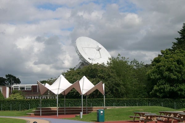 The Jodrell Bank Observatory (originally the Jodrell Bank Experimental Station, then the Nuffield Radio Astronomy Laboratories from 1966 to 1999; /ˈdʒɒdrəl/) is a British observatory that hosts a number of radio telescopes, and is part of the Jodrell Bank Centre for Astrophysics at the University of Manchester. The observatory was established in 1945 by Sir Bernard Lovell, a radio astronomer at the University of Manchester who wanted to investigate cosmic rays after his work on radar during the Second World War. It has since played an important role in the research of meteors, quasars, pulsars, masers and gravitational lenses, and was heavily involved with the tracking of space probes at the start of the Space Age. The managing director of the observatory is Professor Simon Garrington.
The main telescope at the observatory is the Lovell Telescope, which is the third largest steerable radio telescope in the world. There are three other active telescopes located at the observatory; the Mark II, as well as 42 ft (13 m) and 7 m diameter radio telescopes. Jodrell Bank Observatory is also the base of the Multi-Element Radio Linked Interferometer Network (MERLIN), a National Facility run by the University of Manchester on behalf of the Science and Technology Facilities Council.
The site of the observatory, which includes the Jodrell Bank Visitor Centre and an arboretum, is located in the civil parish of Lower Withington (the rest being in Goostrey civil parish), near Goostrey and Holmes Chapel, Cheshire, North West England. It is reached from the A535. An excellent view of the telescope can be seen by travelling by train, as the main line between Manchester and Crewe passes right by the site, with Goostrey station being only a short distance away.
