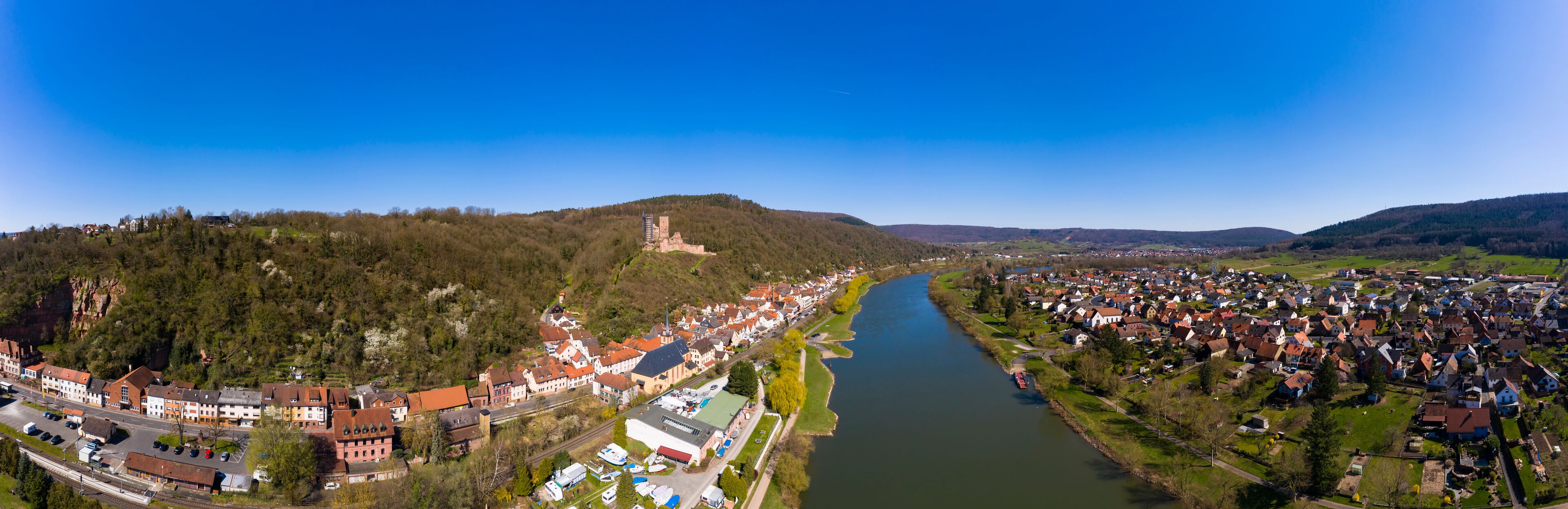 A river flowing through a town with a castle on a hill and dense residential areas.