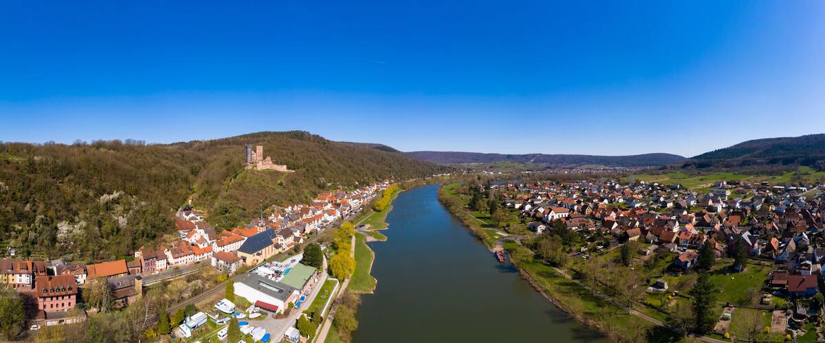 A river flowing through a town with a castle on a hill and dense residential areas.