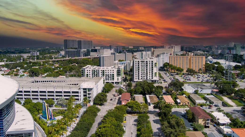 stunning aerial view with hotels, office buildings, apartments and homes in the city skyline and parking lots and LoanDepot Park surrounded by lush green trees at sunset in Miami Florida