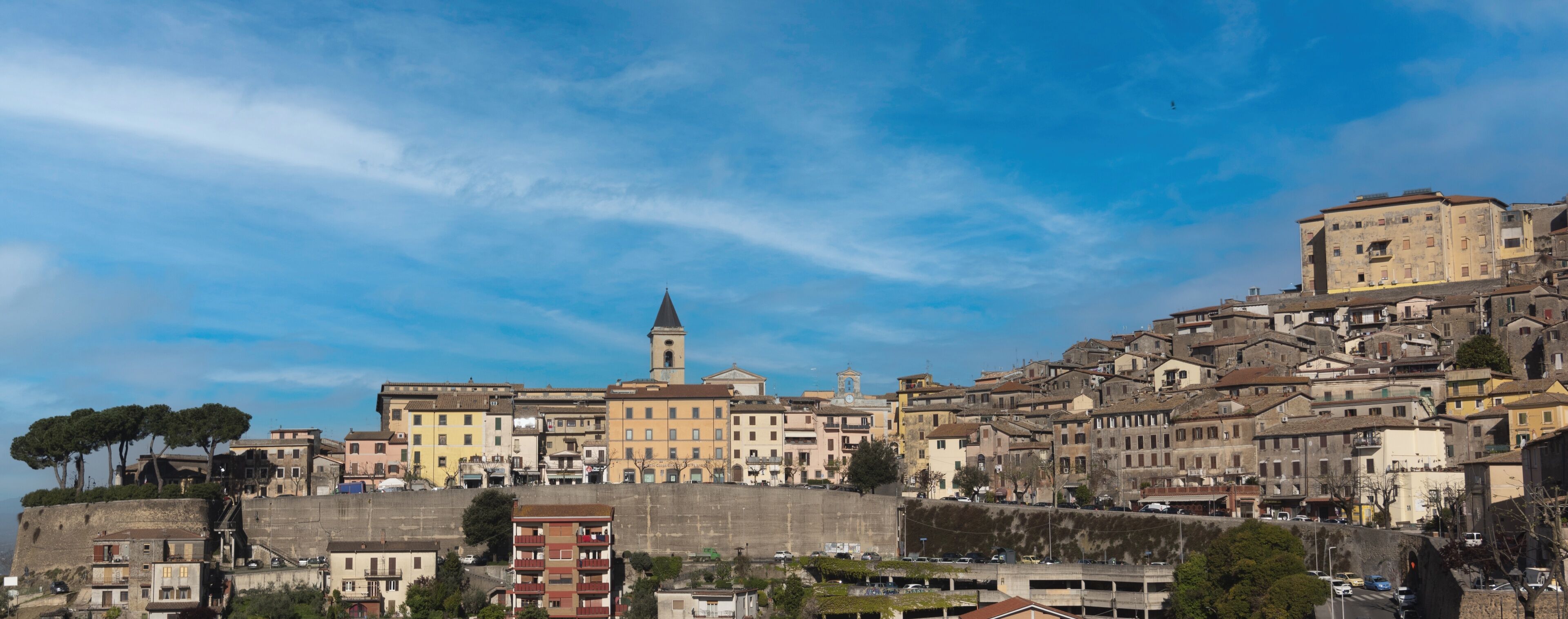 A historic town with a prominent church, a tower, and a densely packed hillside with buildings.