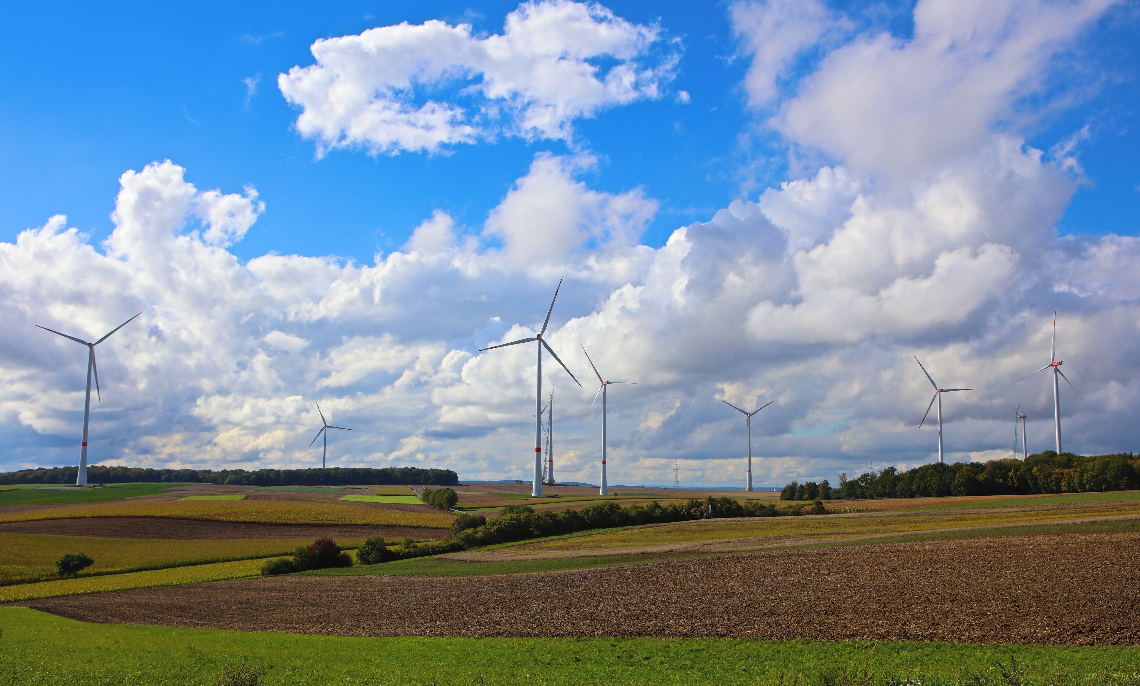 A landscape with wind turbines and fields under a partly cloudy sky.