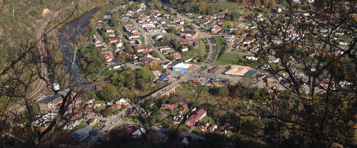A valley with a river, surrounded by hills and a small town with houses and buildings.
