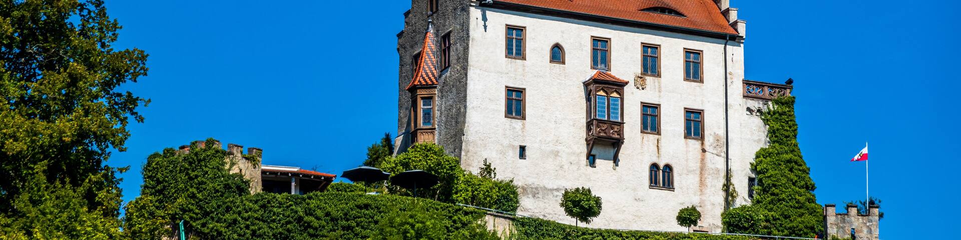 A castle with a red-tiled roof, white walls, and a tower with a flag.