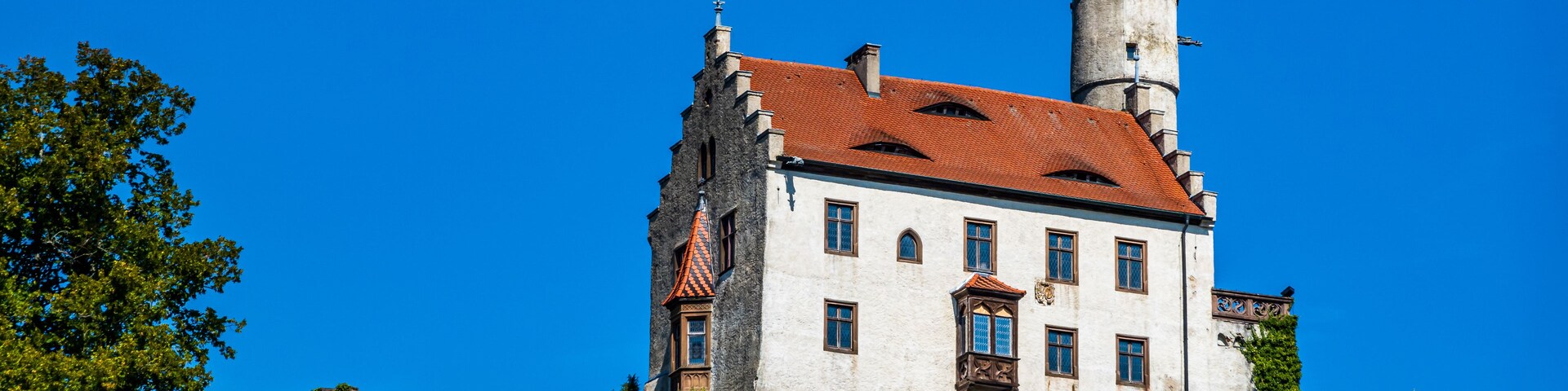 A castle with a red-tiled roof, white walls, and a tower with a flag.