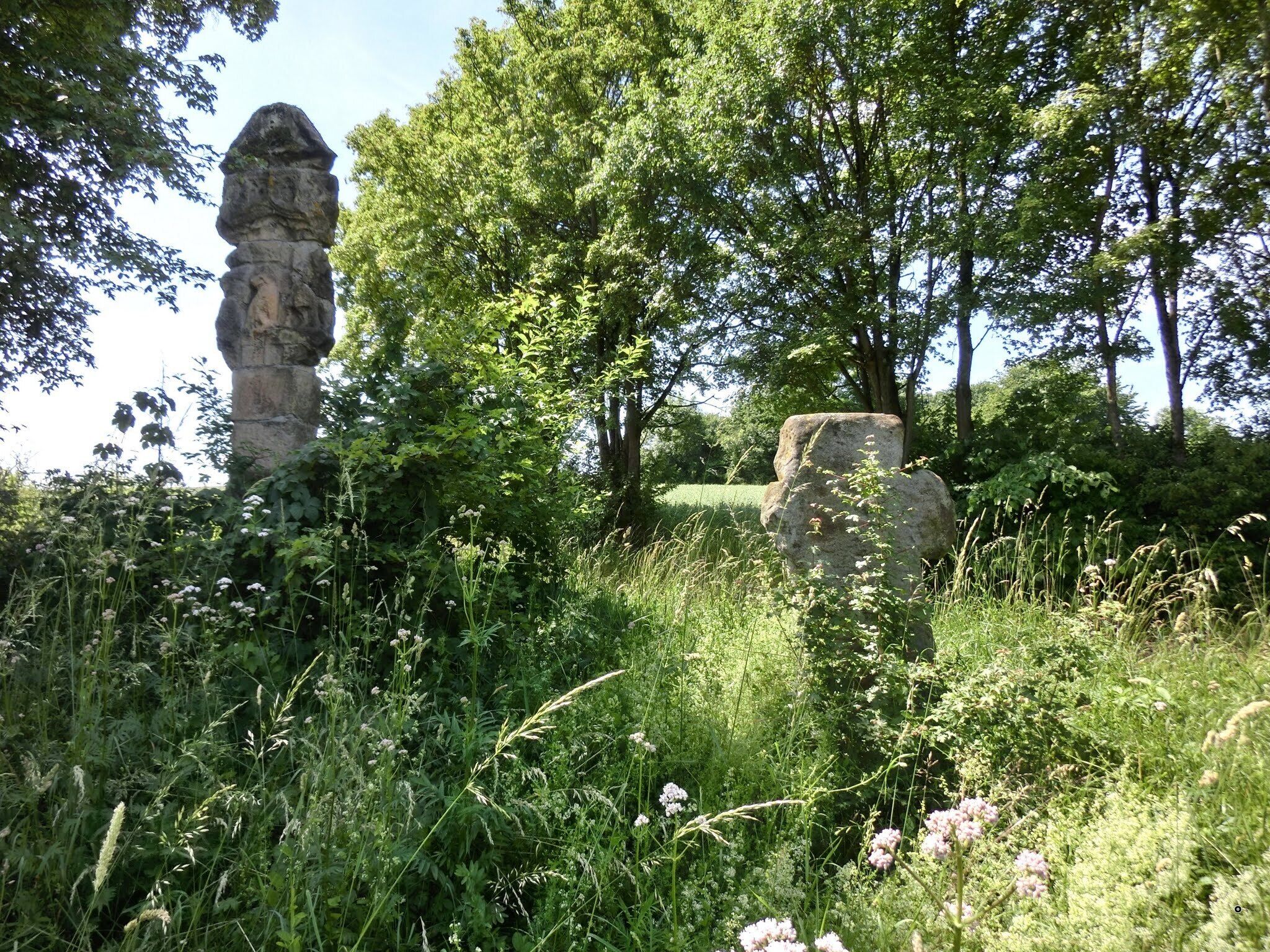 A stone monument surrounded by lush greenery and trees.