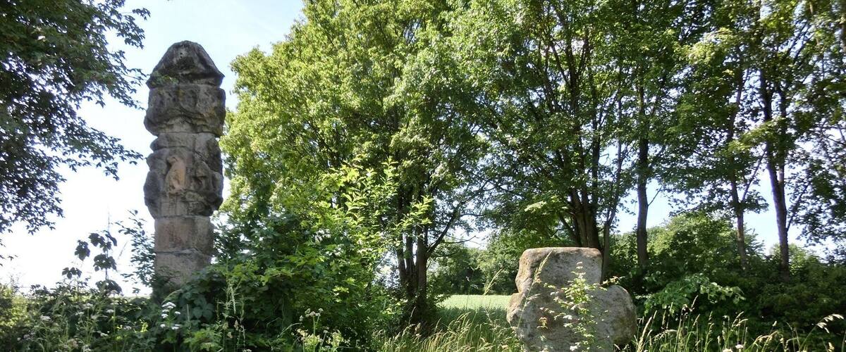 A stone monument surrounded by lush greenery and trees.