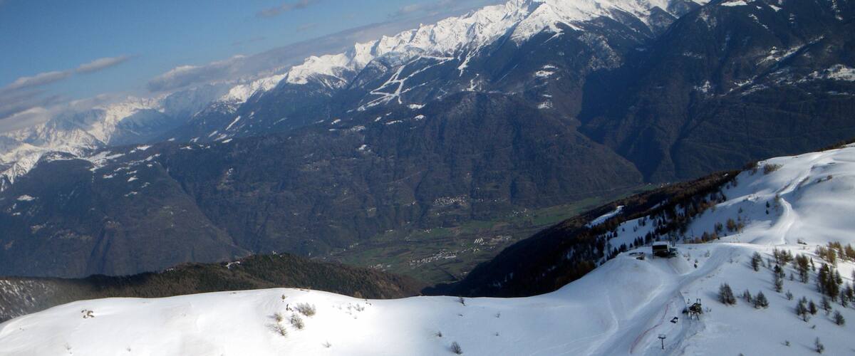 A snow-covered mountain slope with ski tracks and a ski lift.