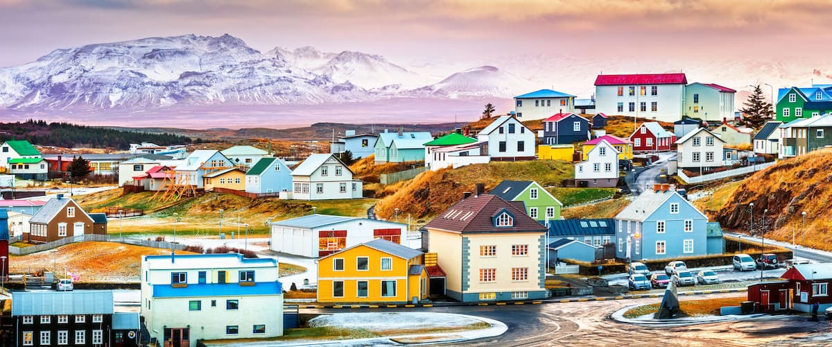 A colorful village with houses and a mountain range in the background.