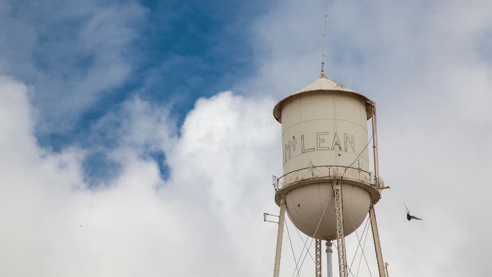 A water tower with the inscription "McLean" against a partly cloudy sky.