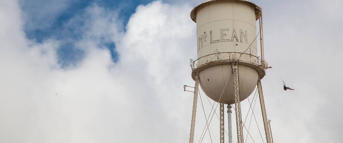 A water tower with the inscription "McLean" against a partly cloudy sky.
