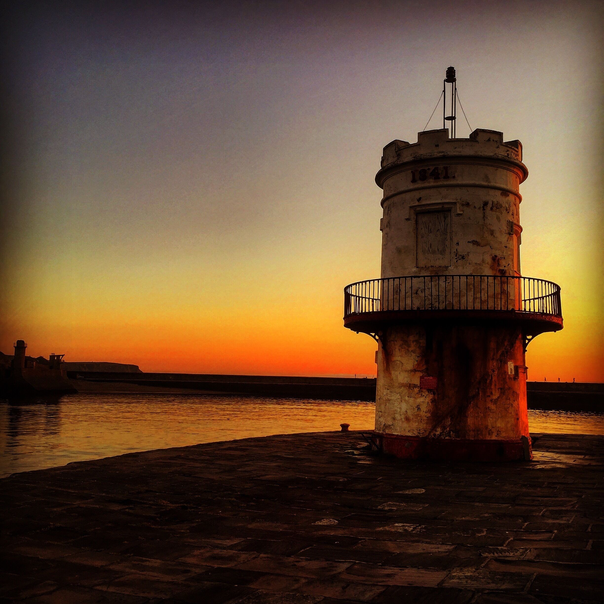 A lighthouse at sunset with a clear sky.