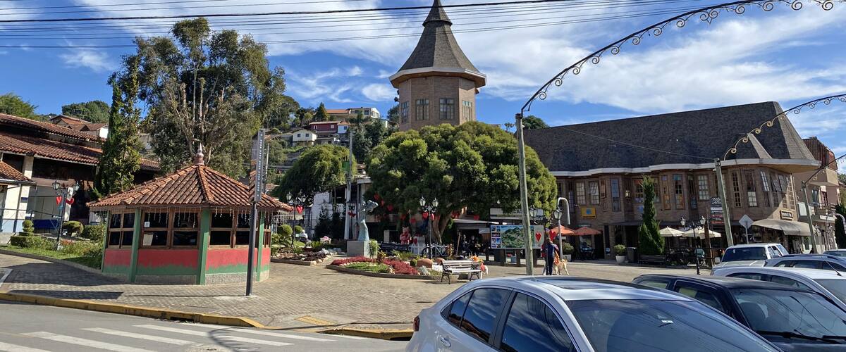 A town square with a gazebo, a church tower, and parked cars.