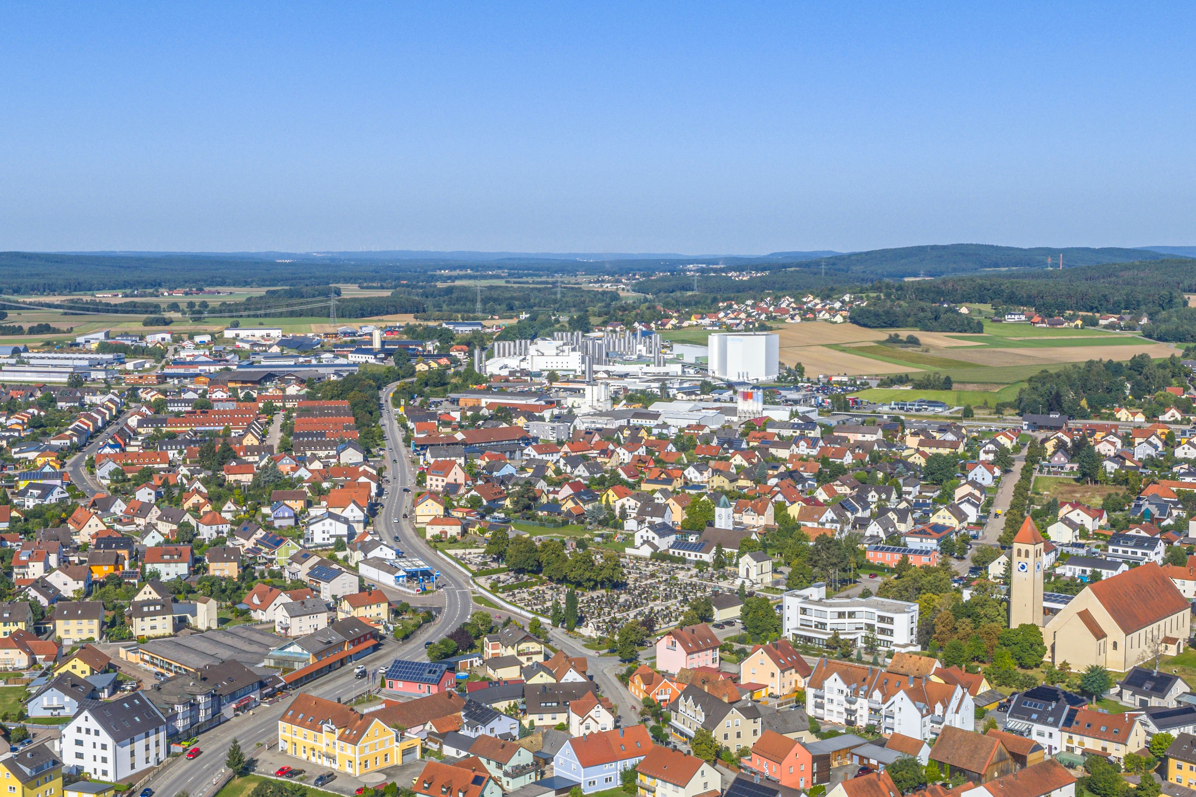 A town with a mix of residential houses, industrial buildings, and a prominent church tower.