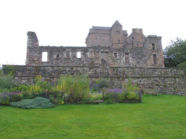 A historic stone castle with ruins and a well-maintained garden in the foreground.