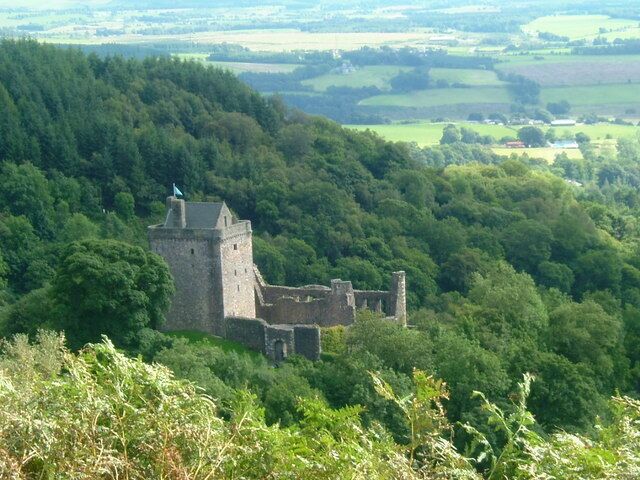 A historic stone castle surrounded by dense forest and rolling hills.