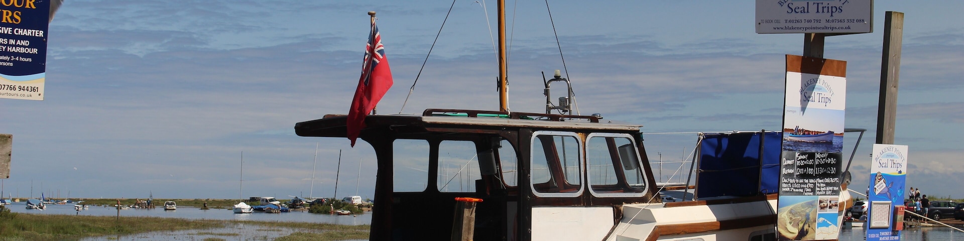 A small boat docked at a pier with a sign for seal trips.