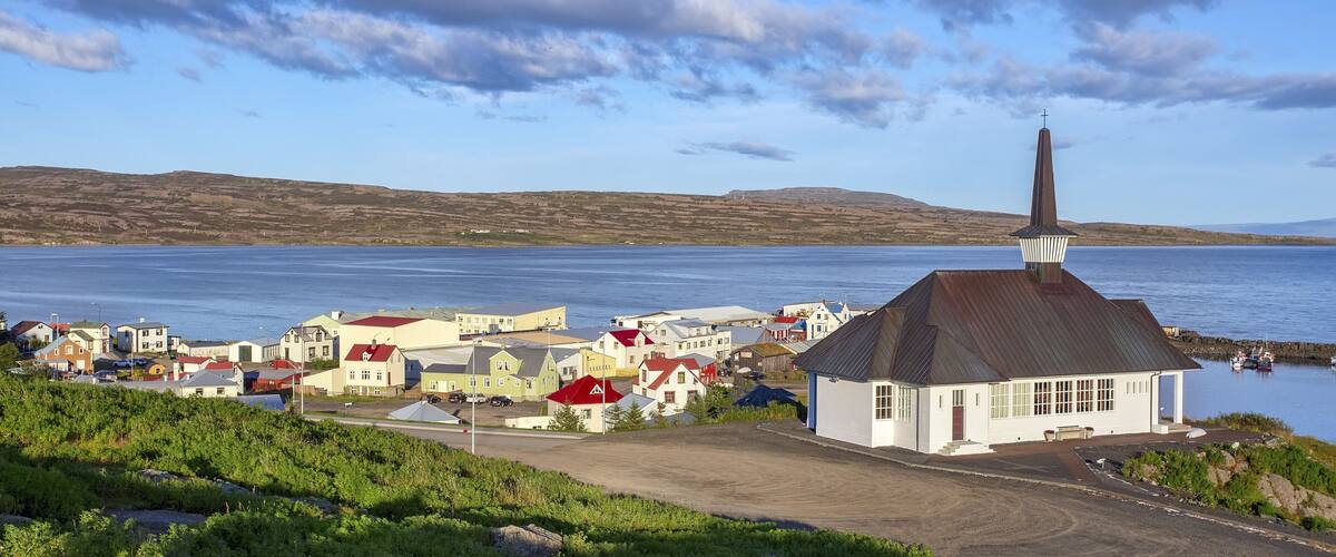 A coastal village with a prominent church, houses, and a calm sea.