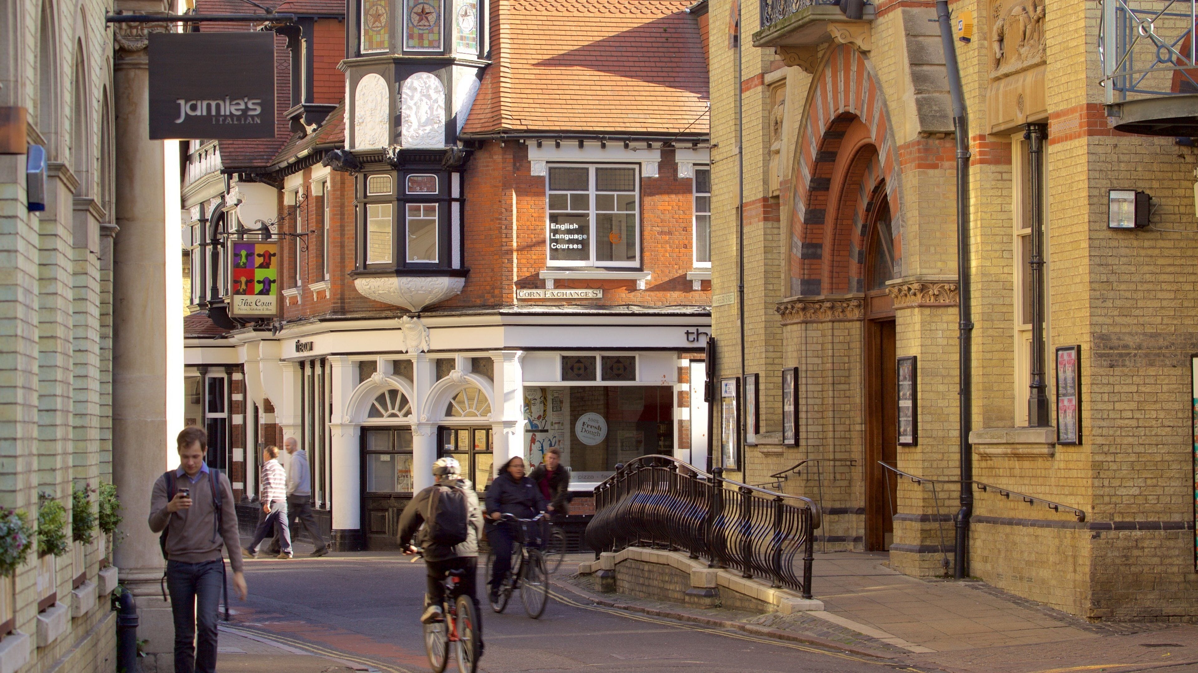 Een straat met historische gebouwen, een fietser en voetgangers.