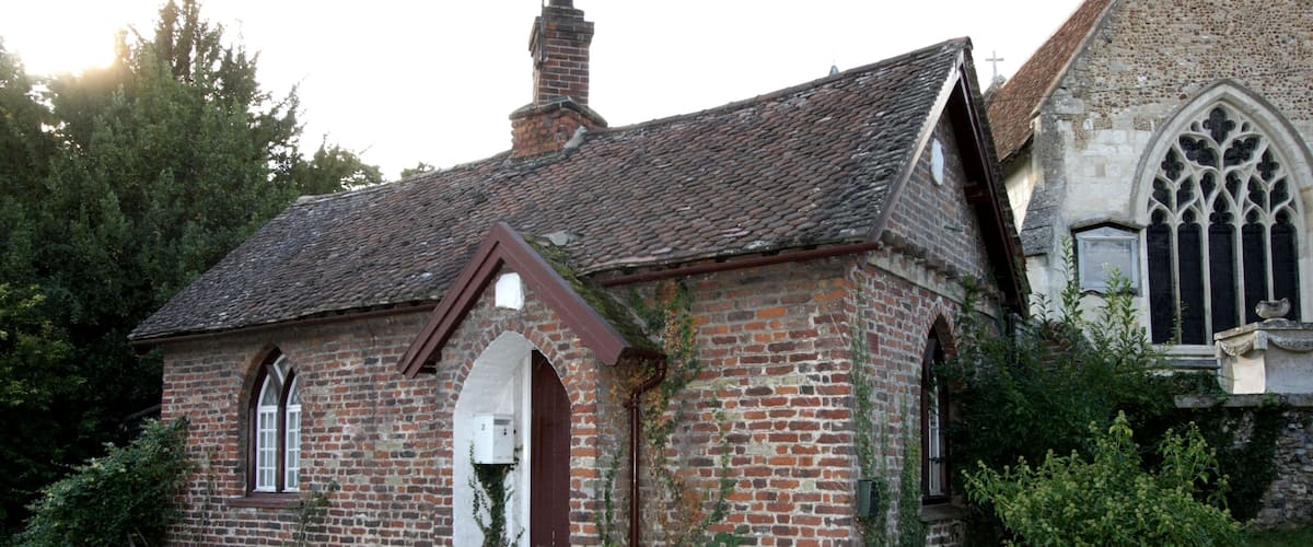 A small brick church with a pointed roof and a large arched window.